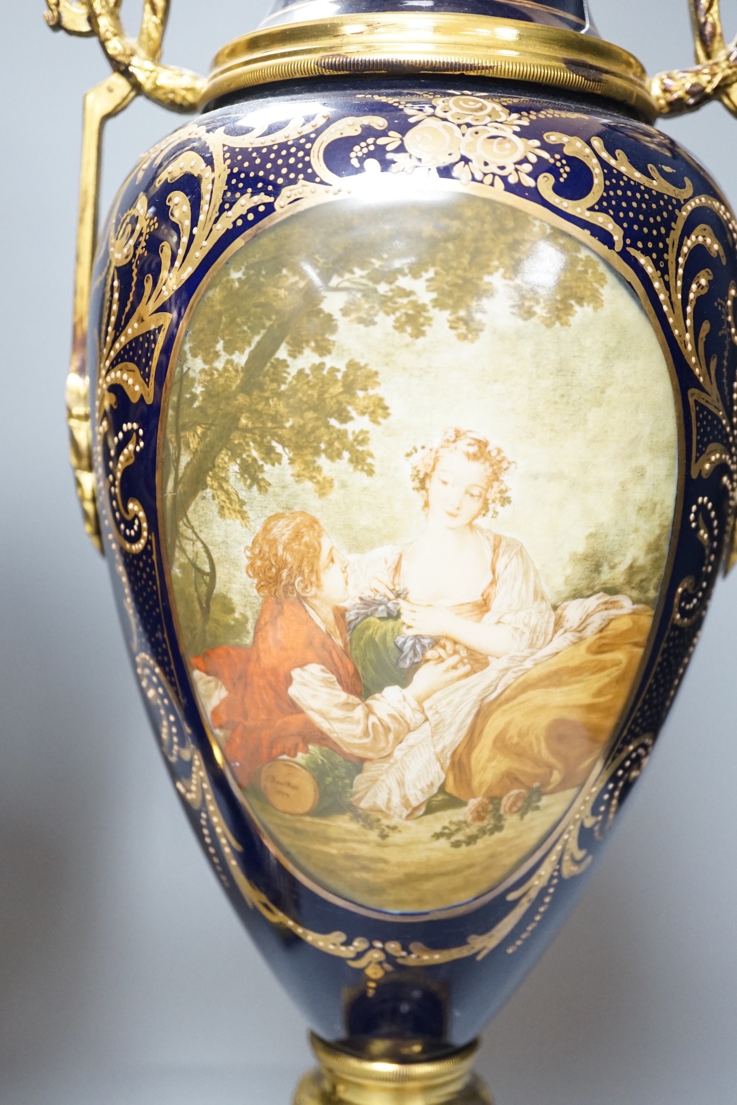 A pair of Sevres style urns and covers, with gilt metal mounts, 50 cms high